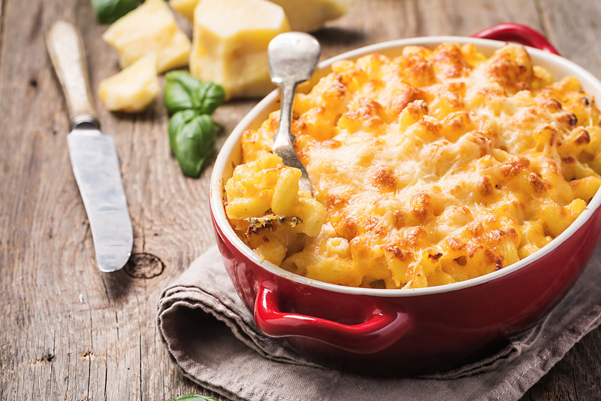 Bowl of macaroni and cheese with crisped cheese topping sitting on top of dish towel