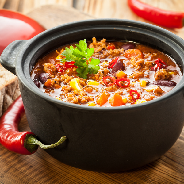 Black cast iron pot of chili with beans, peppers and fresh parsley