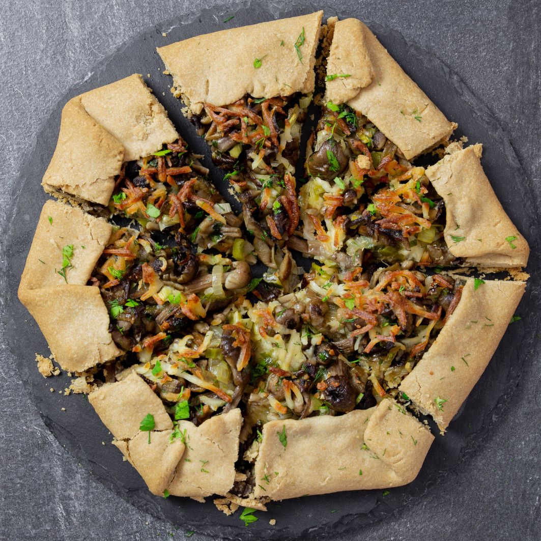 Rustic mushroom galette on a slate board, sliced into wedges
