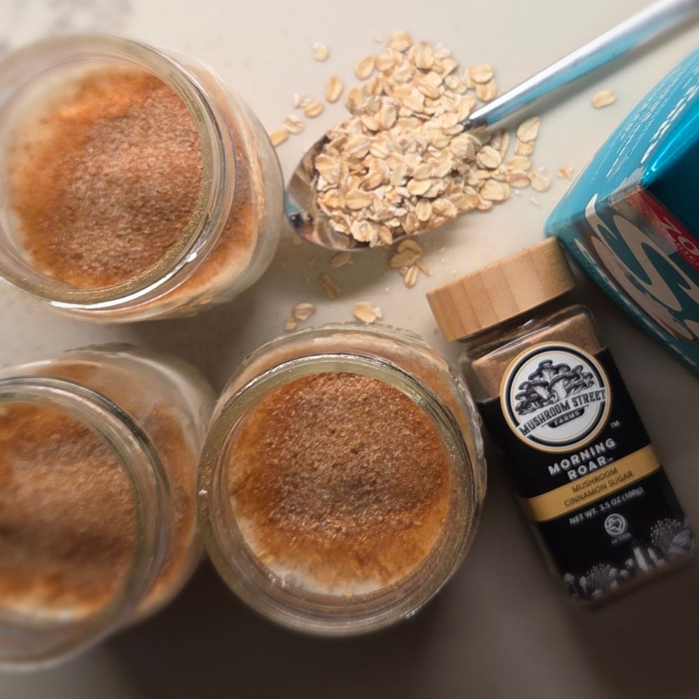 Jars of overnight oats dusted with Morning Roar seasoning, beside the seasoning jar and rolled oats