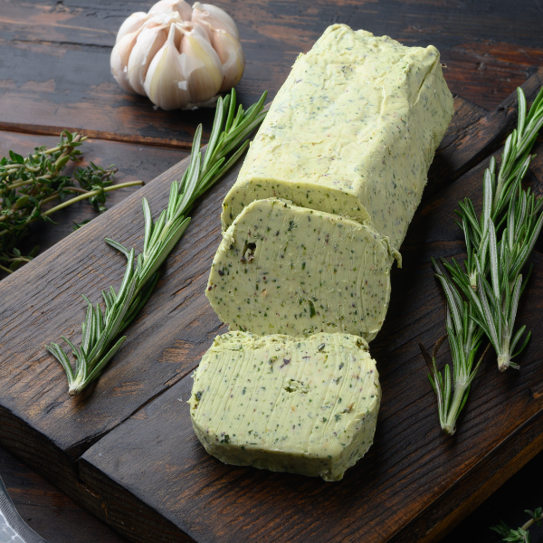 Compound butter infused with fresh herbs sitting on slab of wood