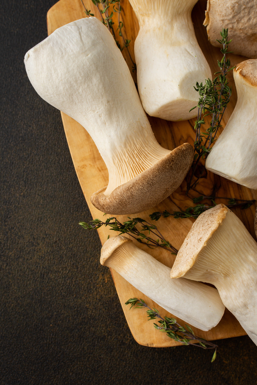 Oyster mushrooms sitting on cutting board with sprigs of rosemary